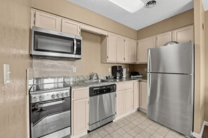 A kitchen with stainless steel appliances, including a microwave, stove, dishwasher, and refrigerator. - Mountain View Condo Near Dollywood | Pools Onsite! (Pigeon Forge)