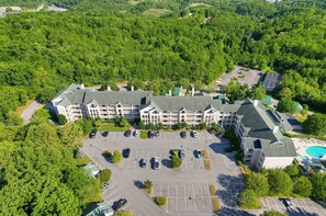 A multi-story hotel with a central courtyard, parking lot, and a swimming pool. - Mountain View Condo Near Dollywood | Pools Onsite! (Pigeon Forge)