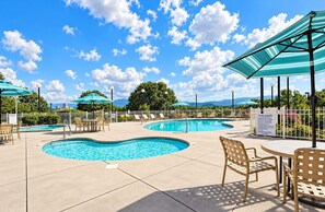 A pool area with multiple swimming pools, lounge chairs, and umbrellas. - Mountain View Condo w/ Balcony | Near Dollywood! (Pigeon Forge)
