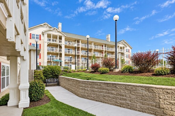 A multi-story residential building with balconies, a landscaped garden, and a paved walkway. - Mountain View Condo w/ Balcony | Near Dollywood! (Pigeon Forge)