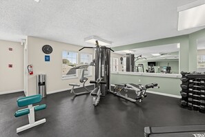 A gym with exercise equipment, a clock, and a fire extinguisher on the wall. - Mountain View Condo w/ Balcony | Near Dollywood! (Pigeon Forge)