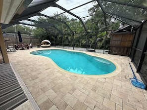 A swimming pool with a curved edge, surrounded by a patio area with seating and a barbecue grill. - Private Lower-Level Suite w/ Pool Access (St. Petersburg)