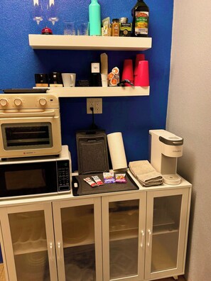 A kitchenette with a microwave, toaster, kettle, and coffee maker. There are shelves above with various items like a bottle, jars, and a tea bag. - Private Lower-Level Suite w/ Pool Access (St. Petersburg)
