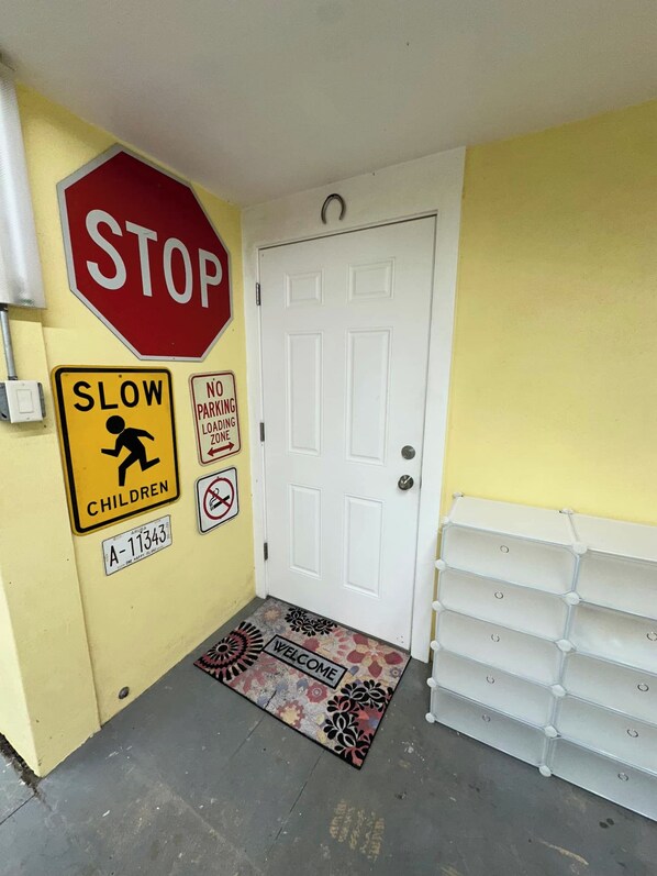 A hallway with a stop sign, a slow children sign, a no parking loading zone sign, and a welcome mat. - Private Lower-Level Suite w/ Pool Access (St. Petersburg)