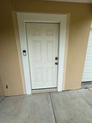 A white door with a simple design, a small mailbox to the left, and a concrete ground. - Private Lower-Level Suite w/ Pool Access (St. Petersburg)