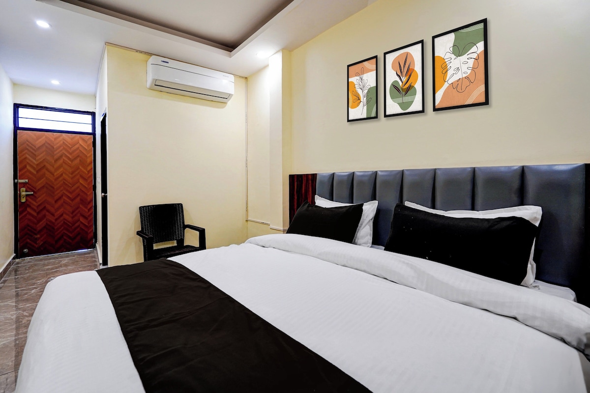 A hotel room with a bed, a chair, a door, and wall art.
