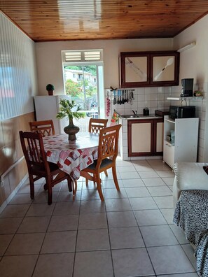A cozy kitchen with wooden cabinets, a dining table with chairs, and a view of the outside. - New Listing (VAUCLIN)