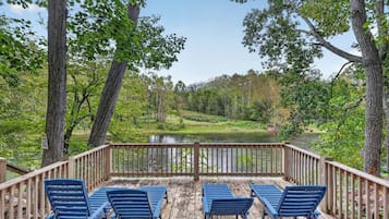 A wooden deck with blue chairs overlooking a river and forest.