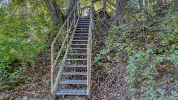 A wooden staircase leading up a rocky hill surrounded by trees and foliage.