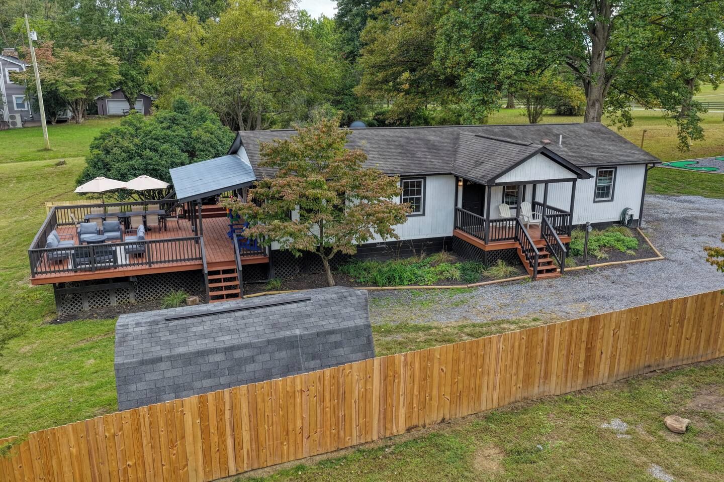 A two-story house with a deck, a covered outdoor seating area, and a front porch.