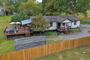 A two-story house with a deck, a covered outdoor seating area, and a front porch. - Riverfront Cabin w/ 9-Hole Mini Golf + Hot Tub (Shenandoah)
