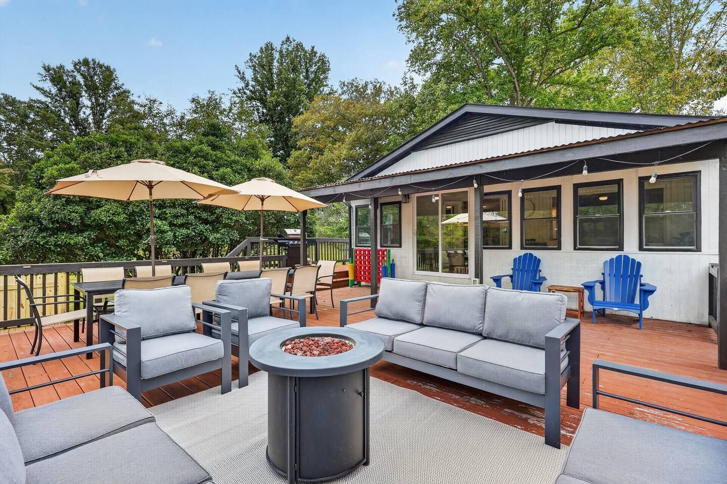 An outdoor deck with a sofa set, a fire pit, and two umbrellas.