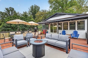 An outdoor deck with a sofa set, a fire pit, and two umbrellas. - Riverfront Cabin w/ 9-Hole Mini Golf + Hot Tub (Shenandoah)
