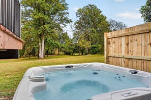 Un jacuzzi dans un jardin, avec une clôture en bois et des arbres.