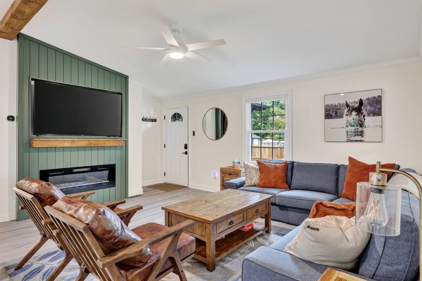A living room with a television, sofa, coffee table, and leather chairs.