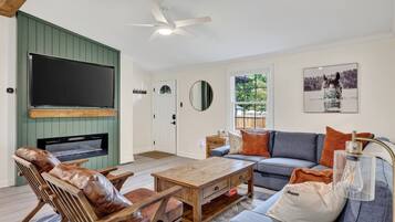 A living room with a television, sofa, coffee table, and leather chairs.
