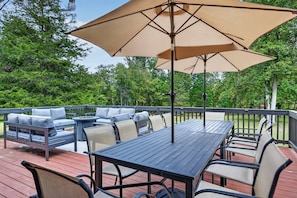 An outdoor deck with a table and chairs, a sofa, and a large umbrella. - Riverfront Cabin w/ 9-Hole Mini Golf + Hot Tub (Shenandoah)