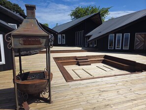 A wooden deck with a metal grill and a fire pit, surrounded by buildings with large windows. - New Listing (Puerto montt)