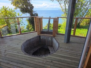 Terraza de madera con jacuzzi y vista al mar.