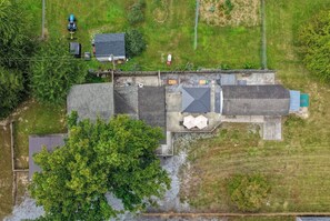 A large building with multiple sections, including a covered outdoor area with tables and umbrellas, surrounded by a fenced property with trees and a gravel path. - Riverfront Cabin - Pickleball, Hot Tub, Game Room (Shenandoah)