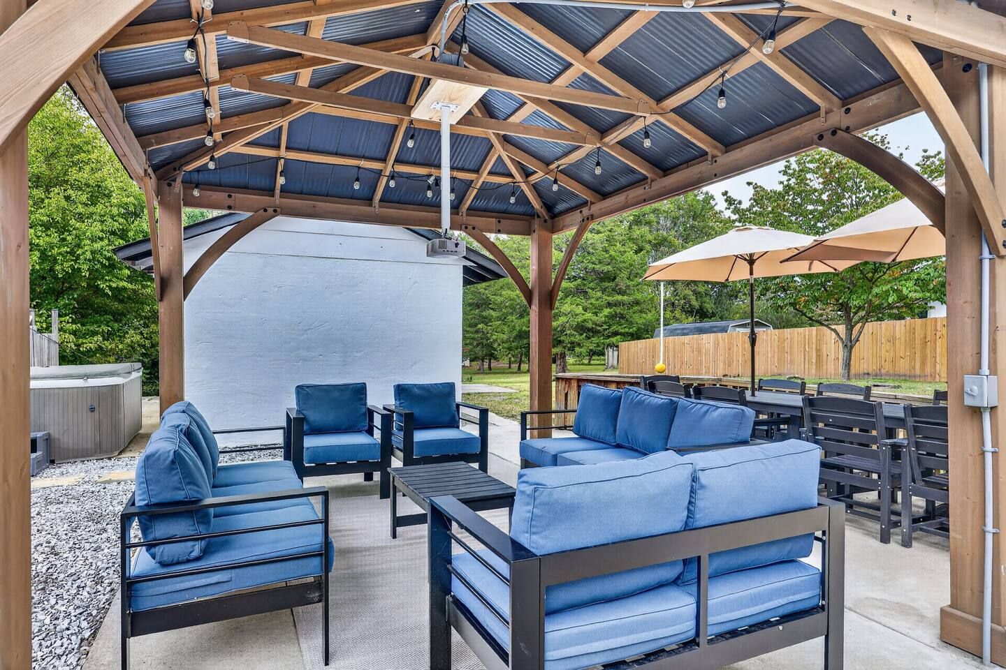 A covered outdoor seating area with a pergola structure, outdoor furniture, and a barbecue grill.