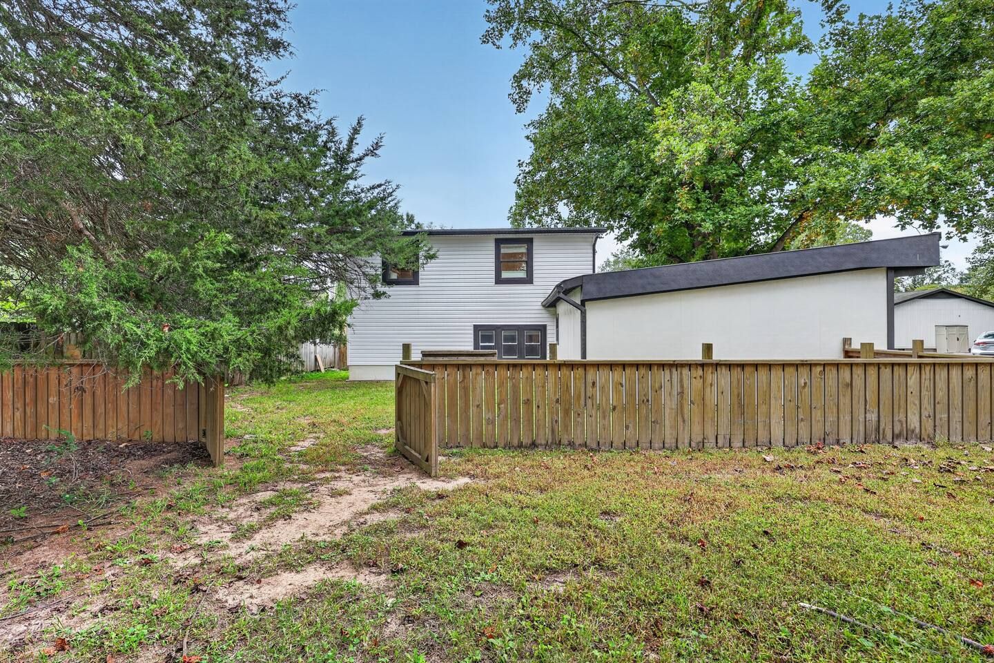 A residential property with a fenced yard, a detached garage, and a house with a gabled roof.