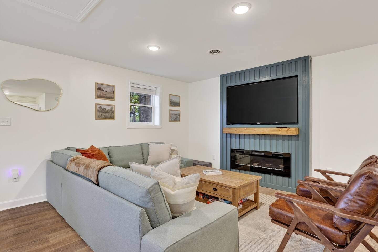 A living room with a sofa, a coffee table, a TV mounted on a blue wall, and a fireplace.