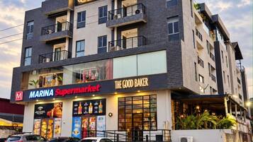 Un immeuble à plusieurs étages abritant un supermarché et une boulangerie au rez-de-chaussée, ainsi qu’un port de plaisance.