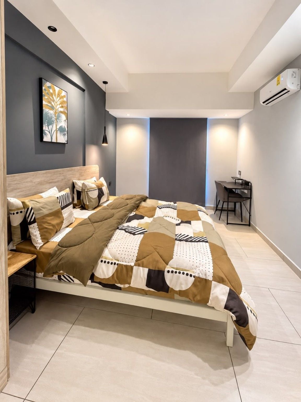 Un dormitorio moderno con una cama grande, un escritorio y un equipo de aire acondicionado.