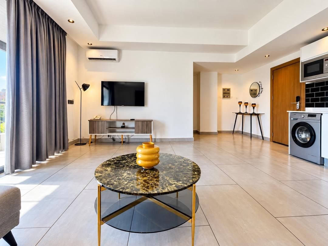 Una sala de estar moderna con una mesa redonda, un televisor de pantalla plana y una lavadora.