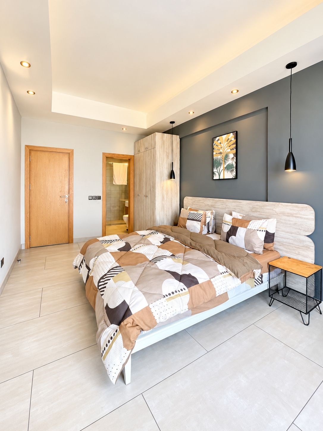 Une chambre à coucher moderne, avec un grand lit, une table de chevet, une armoire et une salle de bain visible à travers une porte ouverte.