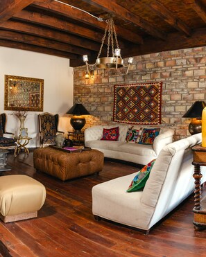 Un salon chaleureux avec un mur en briques, un luminaire suspendu et un tapis à motifs.