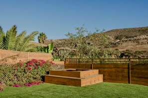 A landscaped garden with a wooden bench, a wooden fence, and a variety of plants including a cactus. - Long Stay Cabin 1 - by Hacienda Cuatro Milpas (Ensenada)