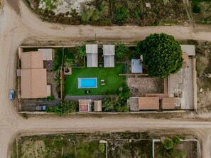An aerial view of a property with a swimming pool, a large tree, and a mix of residential and commercial buildings. - Long Stay Cabin 1 - by Hacienda Cuatro Milpas (Ensenada)
