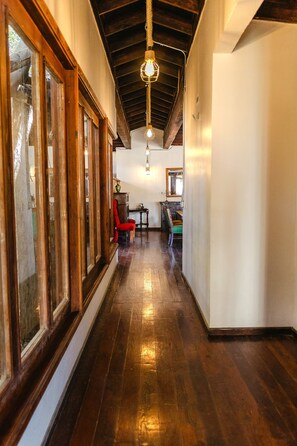 A hallway with wooden floors, a red chair, and a table with a vase. - Long Stay Cabin 1 - by Hacienda Cuatro Milpas (Ensenada)