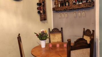 Ein Essbereich mit Holztisch, Stühlen, einer Uhr, Weinflaschen und rustikaler Wandgestaltung.