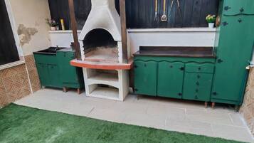 Eine Terrasse mit integriertem Grill und grünen Schränken.