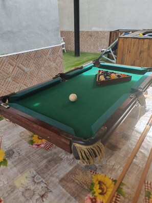 A pool table with a cue ball, surrounded by a patterned floor and a wooden structure. - New Listing (Roma)