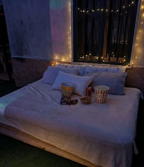 Ein Bett mit Kissen, einer Popcorndose und einer Limodose.