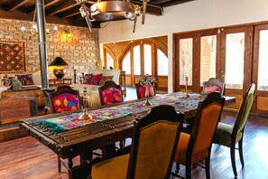 Un coin repas avec une table en bois rustique, des chaises colorées et un mur en briques.