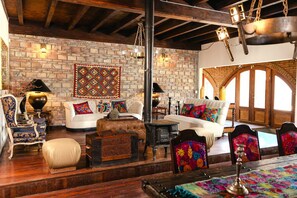 Un salon chaleureux avec une cheminée, un canapé, un tapis à motifs et un plafond en bois.