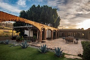 Une cour avec une arche en briques, des sièges extérieurs et une pergola.