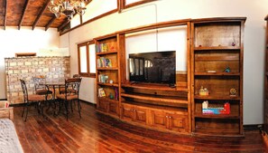 A wooden entertainment unit with a television, bookshelves, and decorative items. - Private Room 2 - Long Stay Hacienda Cuatro Milpas (Ensenada)
