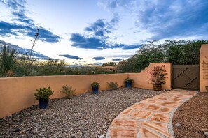 Eine Terrasse mit einem gepflasterten Weg, Kübelpflanzen und Blick auf eine gebirgige Landschaft.