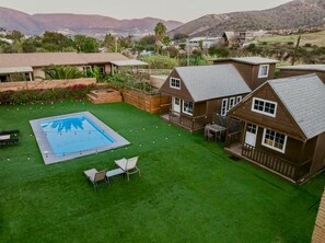 Ein Wohnhaus mit Schwimmbad, einer Terrasse mit Sitzgelegenheit und Blick auf die umliegende Landschaft.