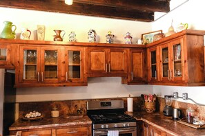 A kitchen with wooden cabinets, a stove, and various kitchen appliances. - Private Room - Long Stay Hacienda Cuatro Milpas (Ensenada)