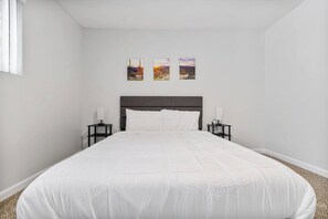 A bedroom with a large bed, two bedside tables, and three wall-mounted paintings. - Convenient Mesa Stay • Close to Everything (Mesa)