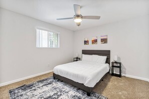 A bedroom with a bed, a ceiling fan, a window, and wall art. - Convenient Mesa Stay • Close to Everything (Mesa)