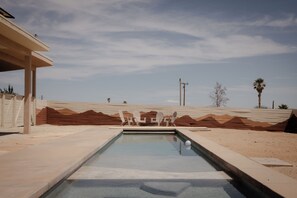 A swimming pool with a clear view of the sky, surrounded by a sandy landscape and a building with a flat roof. - Modern 2-bedroom house with Pool & Spa Joshua Tree (Joshua Tree)