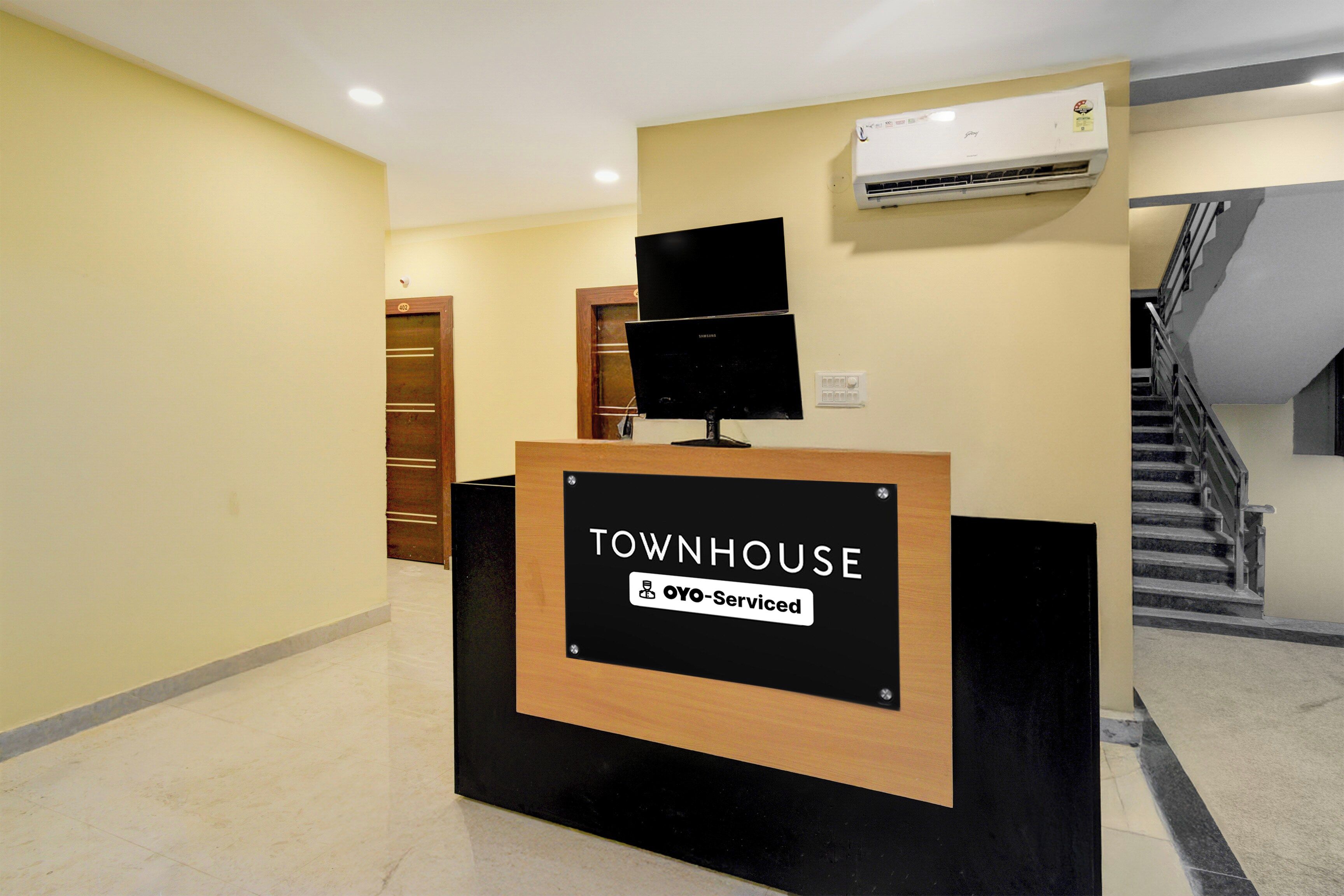 Bancada de recepção com placa indicando serviço YOYO, uma escadaria e um aparelho de ar condicionado na parede.